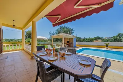 a patio with a table and chairs and a swimming pool at Villa Monte Velho in Albufeira