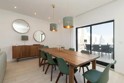 a kitchen with white cabinets and a white table and chairs at Villa Tropicana in Albufeira