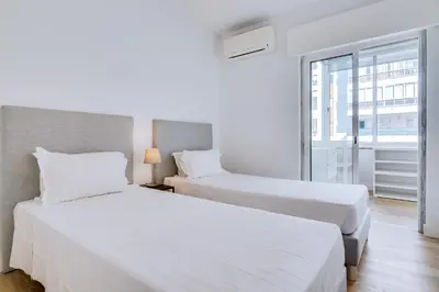 two beds in a hotel room with a window at AL - Apartamento Egas Moniz in Quarteira