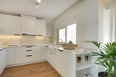 a white kitchen with white cabinets and a plant at Apartamento Boavista - Sea View by DreamvillasAlbufeira in Albufeira