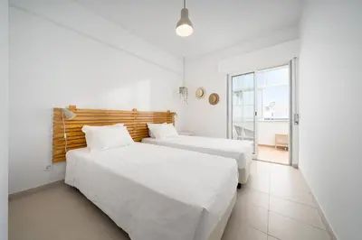 two beds in a white room with a window at AL - Apartamento Vidal Mar in Quarteira
