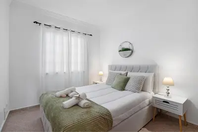 a white bedroom with a teddy bear sitting on a bed at Villa Sunshine in Roja- Pé