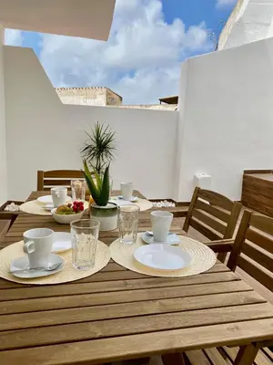 a wooden table with plates and cups on a patio at White Sand Apartments Downtown Albufeira in Albufeira