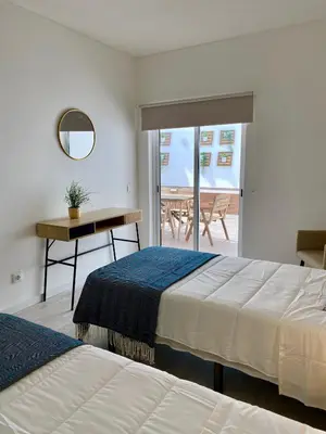 a hotel room with two beds and a table and a balcony at White Sand Apartments Downtown Albufeira in Albufeira