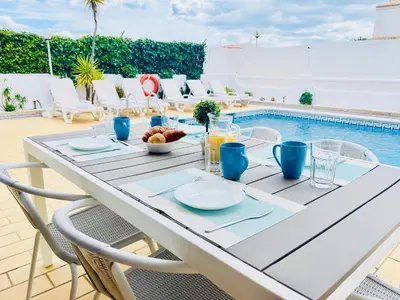 a table with a bowl of fruit on it next to a pool at Villa Cristina 9 in Albufeira
