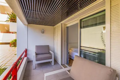 a room with a balcony with a chair and a window at Vista dos Seus Sonhos T2 HsR Vilamarina in Vilamoura