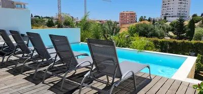 a row of chairs on a deck next to a swimming pool at Villa Ray Design in Albufeira