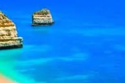 a boat in the water with a rock in the water at Casa da Praia dos Pescadores in Albufeira