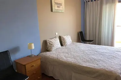 a bedroom with a bed and a chair and a window at Vacations home Albufeira in Albufeira