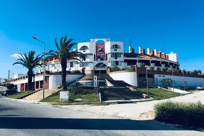 a large white building with palm trees in front of it at Vacations home Albufeira in Albufeira