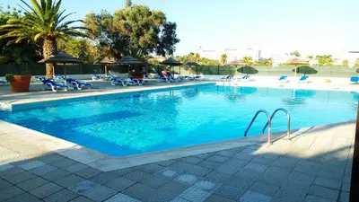 a large swimming pool with chairs and palm trees at Albufeira 603 in Albufeira