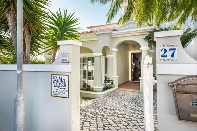 a white house with a gate and palm trees at Rosal 27 by Algarve Villa Holidays in Albufeira
