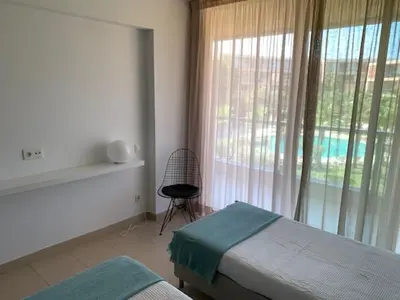 a bedroom with a bed and a window and a chair at Ambassador Salgados Beach Suites in Albufeira
