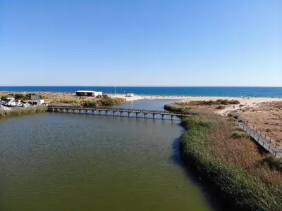 a bridge over a body of water next to a beach at Ambassador Salgados Beach Suites in Albufeira