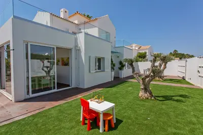a white house with a green yard with a table and chairs at Villa Maresia Dourada in Guia