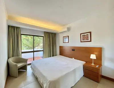 a bedroom with a bed and a chair and a window at Alvaflor - Vilamoura in Vilamoura
