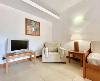 a living room with a tv and a chair at Alvaflor - Vilamoura in Vilamoura