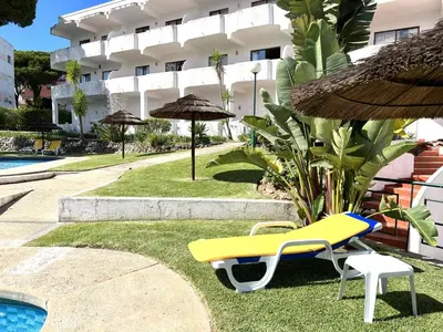 a yellow bench and an umbrella next to a pool at Alvaflor - Vilamoura in Vilamoura