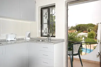 a white kitchen with a sink and a chair at Apartamentos Pedro for Families by Bedzy in Albufeira
