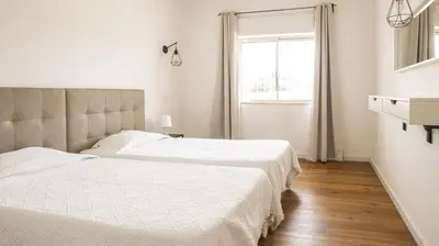 two beds in a white bedroom with a window at Apartamentos Pedro for Families by Bedzy in Albufeira