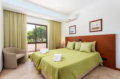 a hotel room with a bed and a window at Host Wise - Bright Cozy Flats w Terrace & Pool in Quarteira