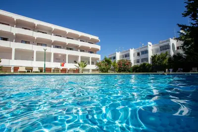 a swimming pool in front of a building at Host Wise - Bright Cozy Flats w Terrace & Pool in Quarteira