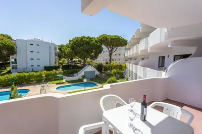 a balcony with a table and chairs and a swimming pool at Host Wise - Bright Cozy Flats w Terrace & Pool in Quarteira