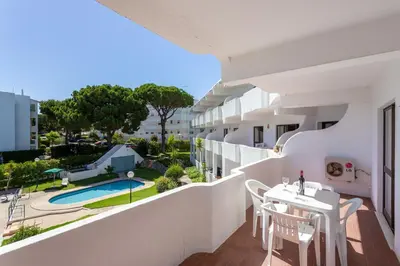 a balcony with a table and chairs and a swimming pool at Host Wise - Bright Cozy Flats w Terrace & Pool in Quarteira