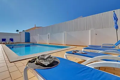 a white table and chairs on a patio with a pool at Villa do Mar - Galé in Albufeira