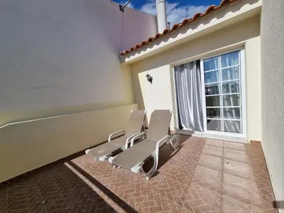 two chairs sitting on a patio with a window at Sea view Penthouse 10 min walking Albufeira old town and Beach Pescadores in Albufeira