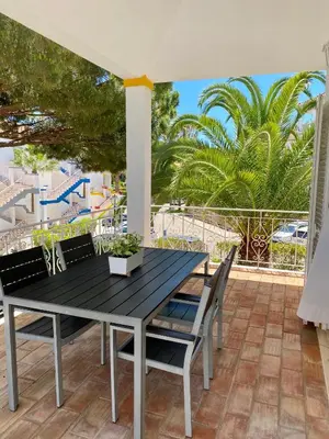 a table and chairs on a patio with palm trees at Beautiful apartment for rent in Quinta do Lago with excellent resort facilities close to lake and beach. in Quinta do Lago