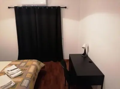 a bedroom with a desk and a black curtain at Minha casa in Faro