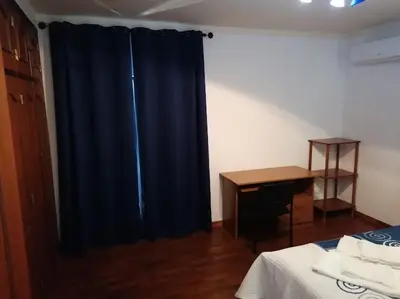 a bedroom with a blue curtain and a desk at Minha casa in Faro