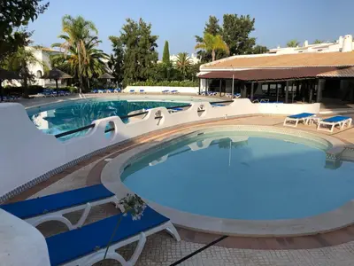 a large swimming pool with chairs and a building at Appartement Sao Rafael praia Algarve portugal in Albufeira