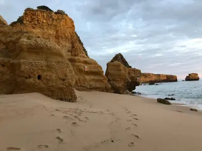 a sandy beach with rocks and footprints in the sand at Appartement Sao Rafael praia Algarve portugal in Albufeira