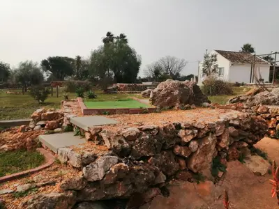 a white bench sitting in a park with a rock wall at Quinta do Medronhal Faro - casas de férias medronhal in Faro
