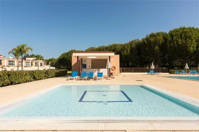 a swimming pool with blue chairs and a house at Apartamento Monte Laguna in Vilamoura