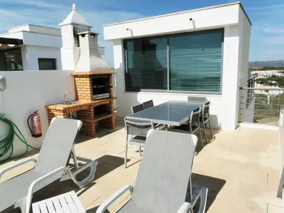 a patio with a table and chairs and a grill at Vila Falesia Penthouse in Albufeira