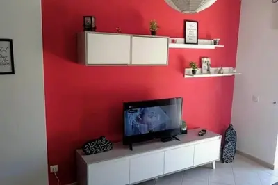 a living room with a tv on a red wall at Falesia - near the beach - The GAVEL Apartment in Albufeira