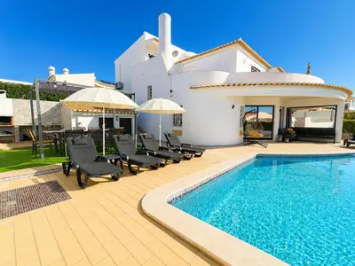a beach with chairs and umbrellas and the ocean at Villa Cristina 17 - 500 m from the Beach in Albufeira