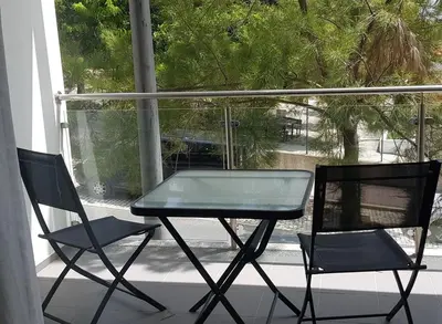 a glass table and two chairs on a balcony at 