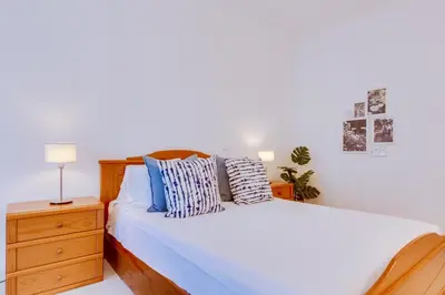 a bedroom with a white bed and a nightstand and a bed sidx sidx sidx at Colina Sol T2 Quarteira Beach in Quarteira