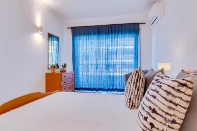 a bedroom with a bed with a blue curtain at Colina Sol T2 Quarteira Beach in Quarteira