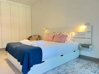 a bedroom with a large white bed with pink pillows at Gardens Side By FHR piscina, parking in Quarteira