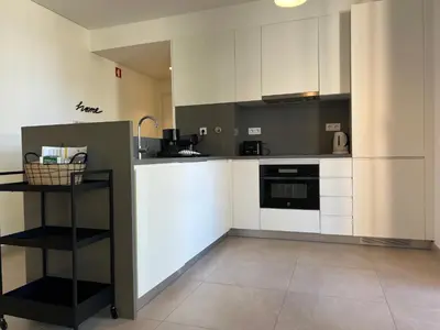 a kitchen with white cabinets and a black counter top at Gardens Side By FHR piscina, parking in Quarteira