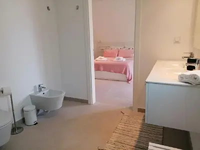 a bathroom with a sink and a bed in a room at Gardens Side By FHR piscina, parking in Quarteira