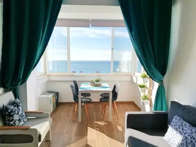 a living room with a table and a large window at Mira Praia, Sunny and Sea in Quarteira