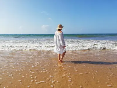 a woman in a white dress standing on the beach at Mira Praia, Sunny and Sea in Quarteira