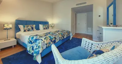 a bedroom with a bed and two wicker chairs at Victory Village 18E in Quinta do Lago