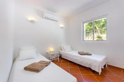 two beds in a white room with a window at Villa AL Fresco in Guia
